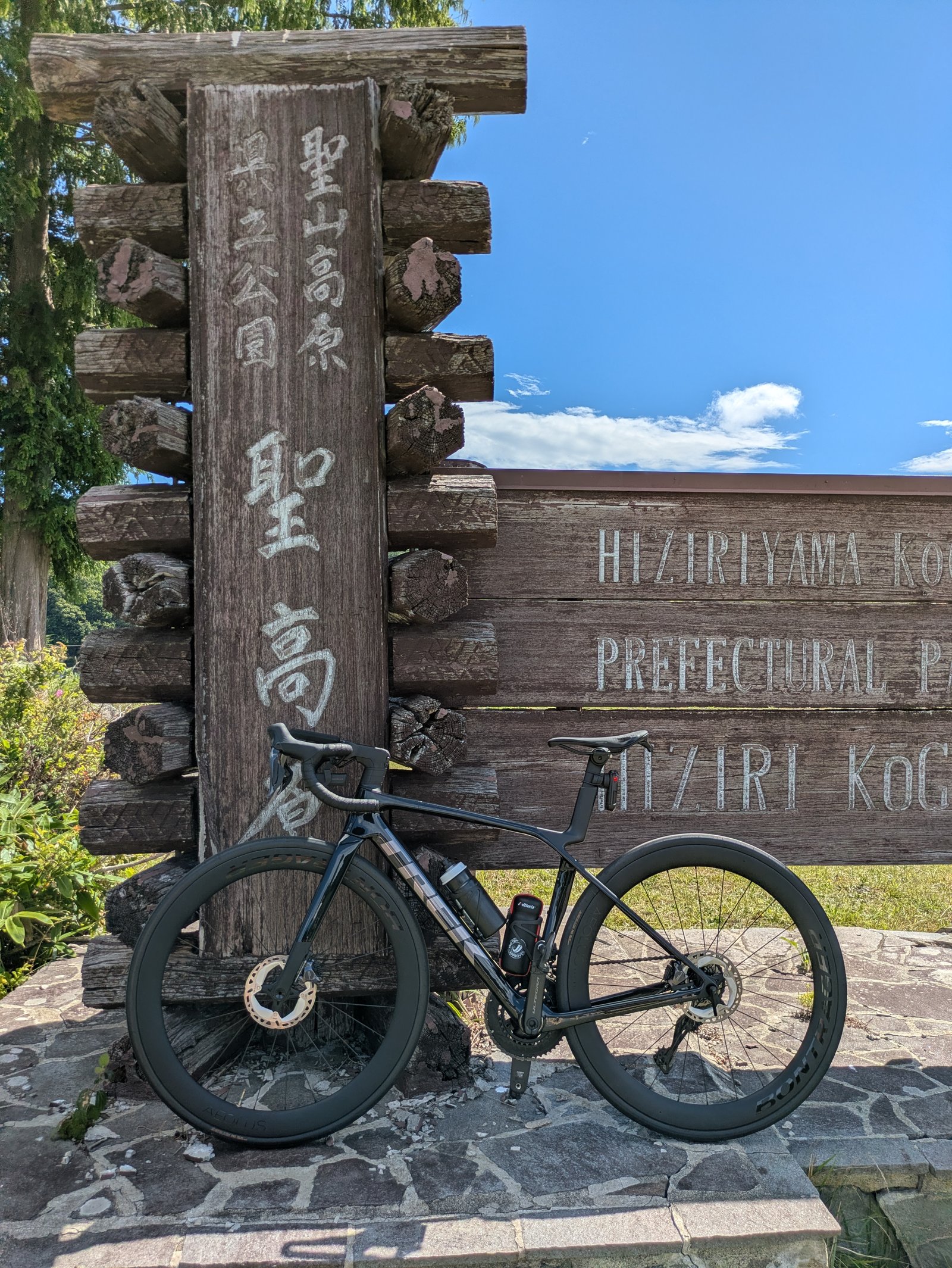 長野の高原の看板の前に立てかけたロードバイク